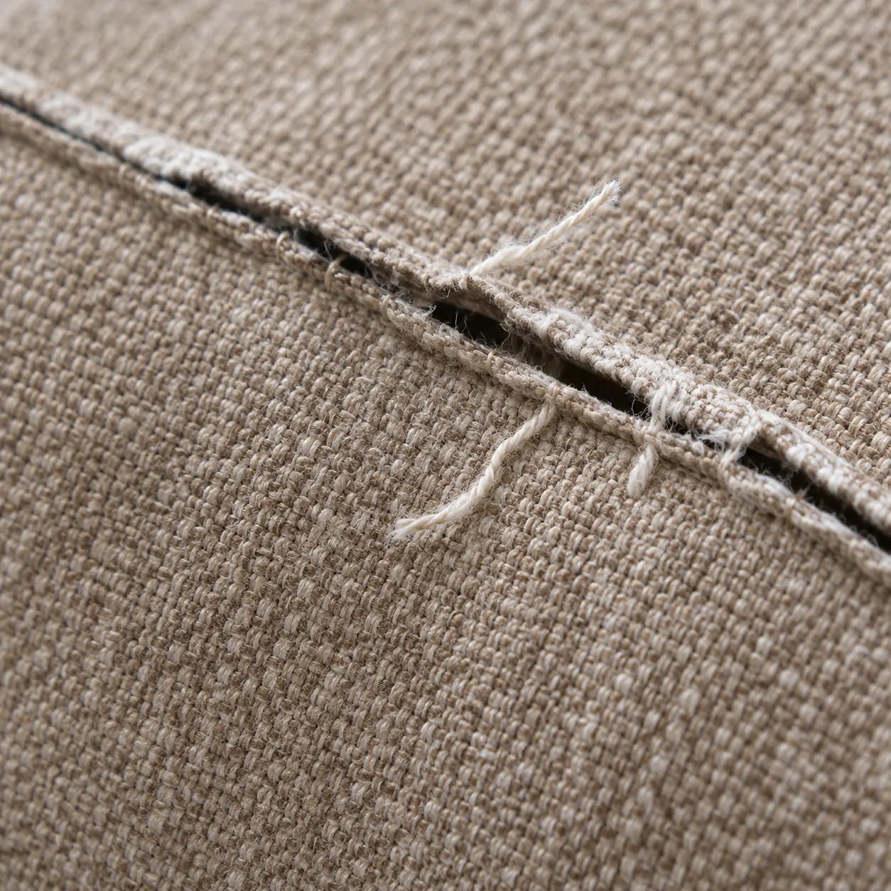 Split seam on an upholstered headboard with frayed threads along the opening