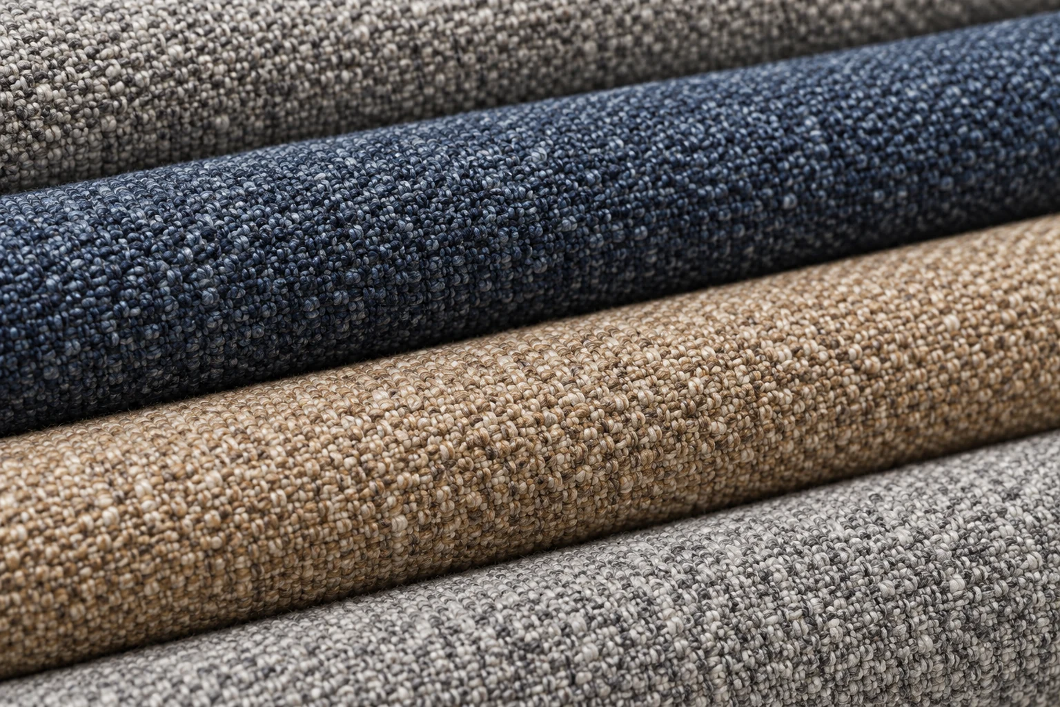 Stacked textured upholstery fabric swatches in blue, grey and oatmeal, folded to show their weave depth