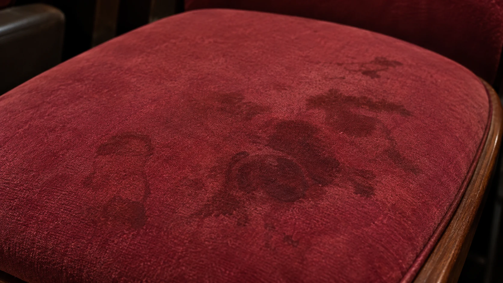 Dark stains on a burgundy velvet theater seat