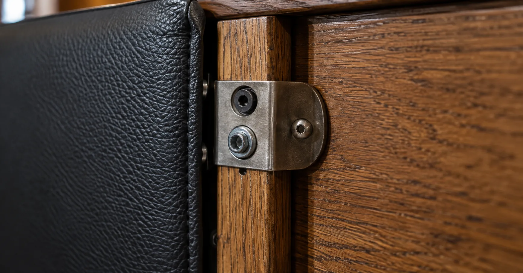 Steel bracket bolting a leather banquette panel to the building