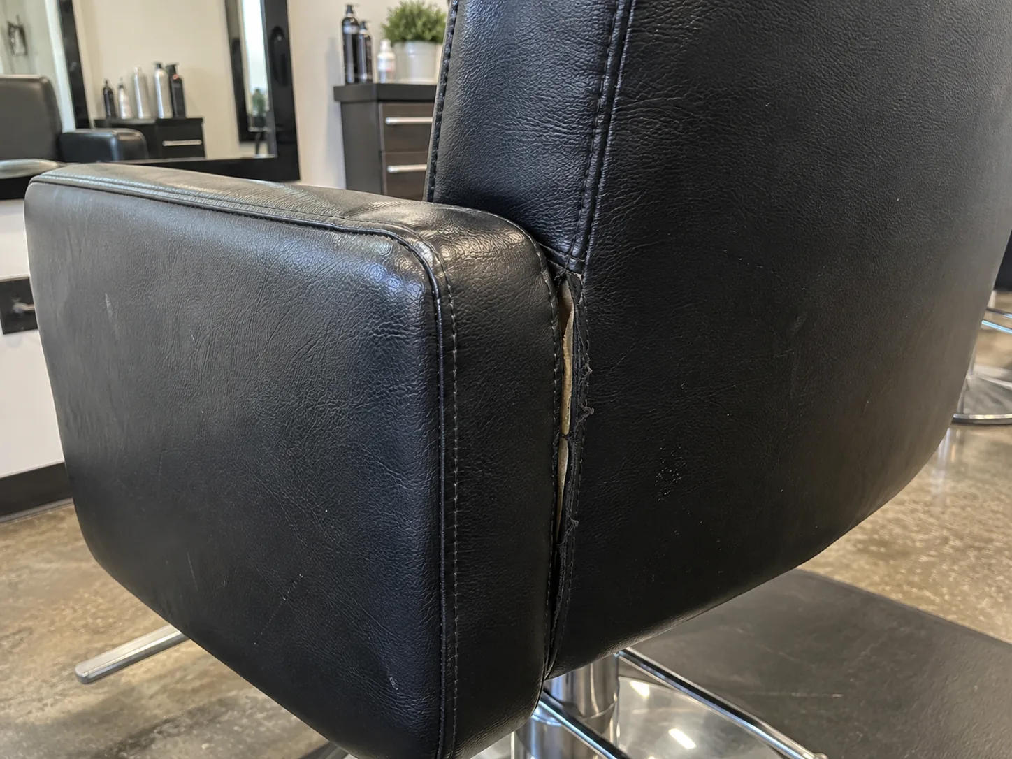 A split seam on the back of a black styling chair
