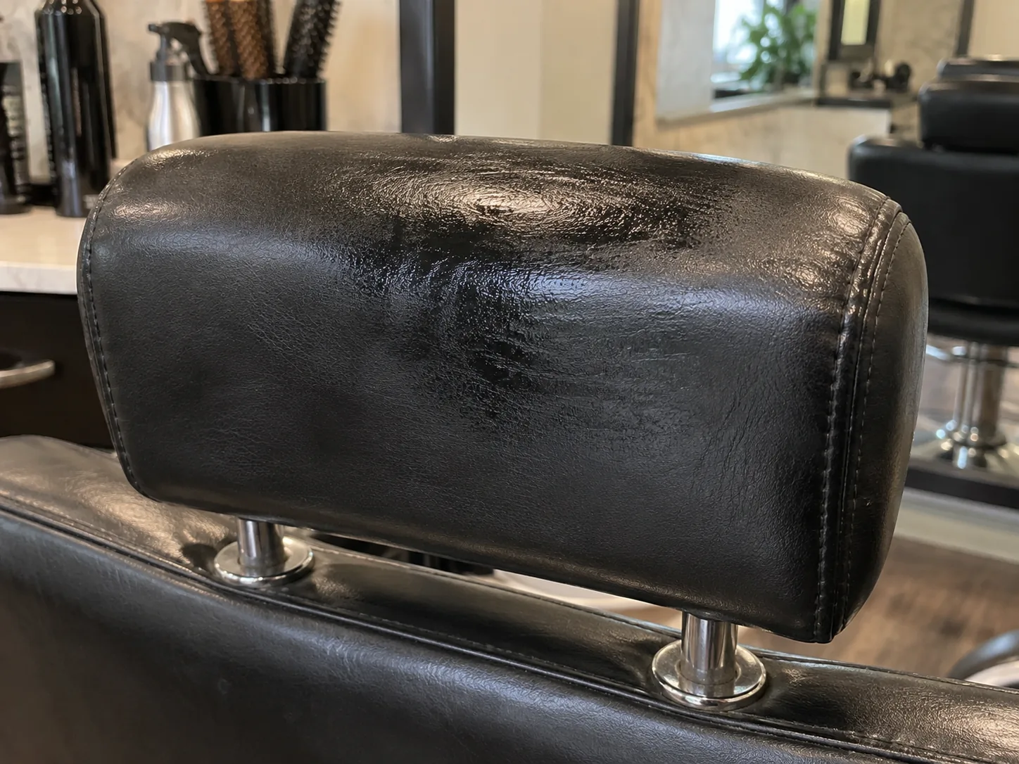 Product residue darkening the vinyl headrest of a black styling chair