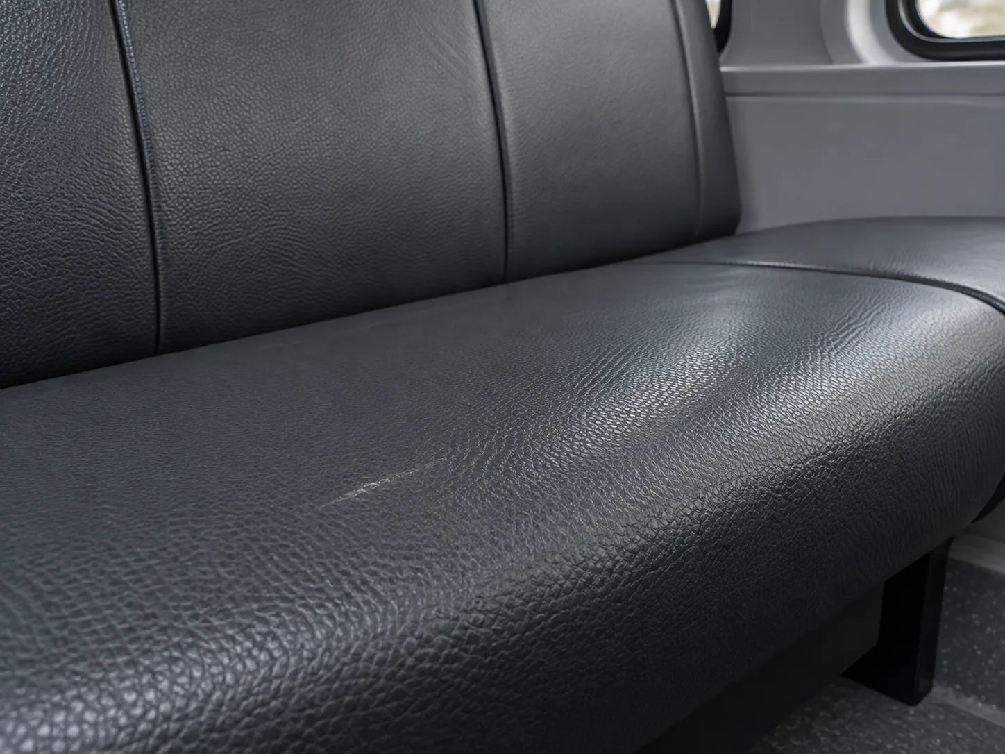 A light scuff and shine mark on a dark vinyl seat