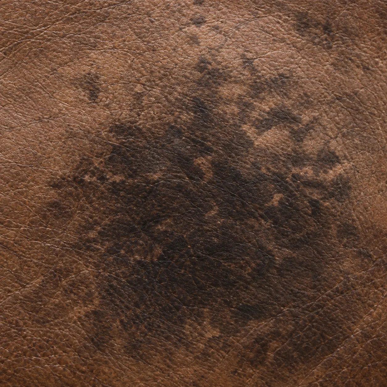 Tan theater seat leather gone blotchy and dark with absorbed soiling
