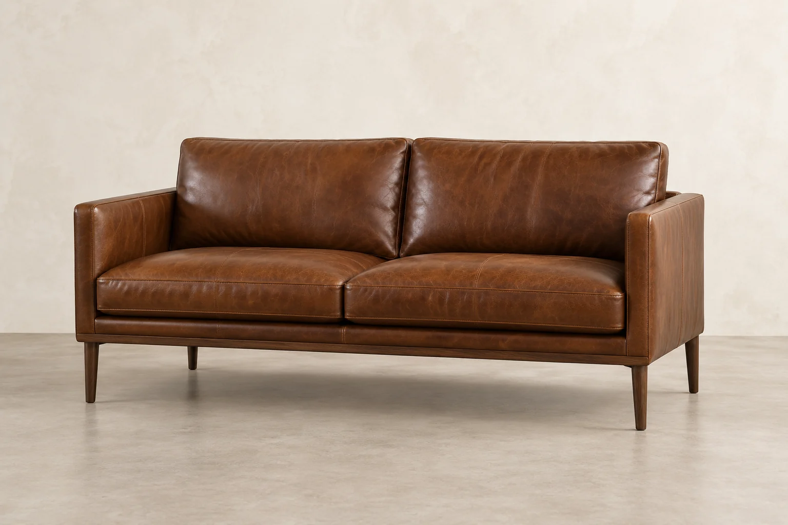 Tan leather two-seat sofa with tapered legs