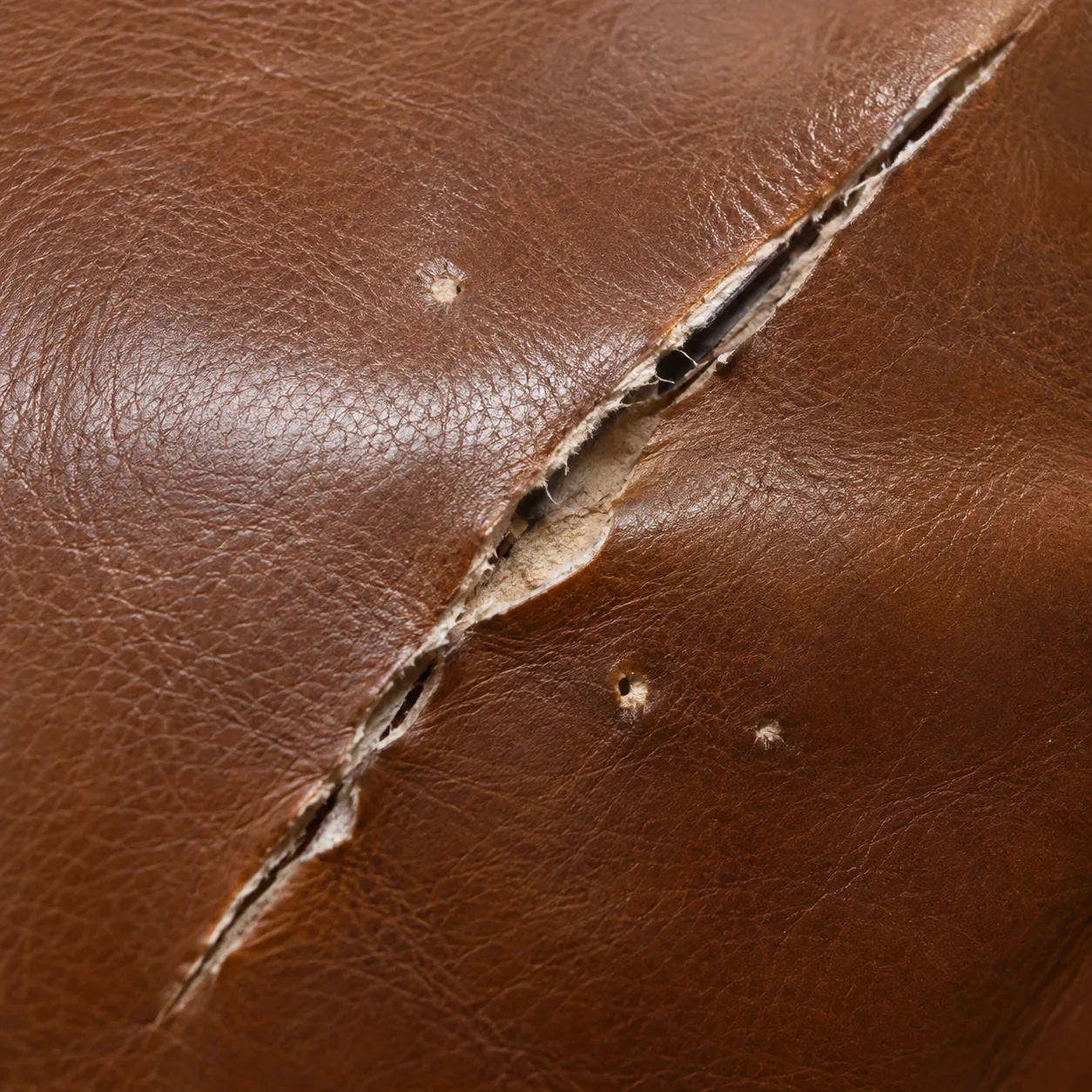 Close-up of a split in a brown leather cushion recorded for a claim