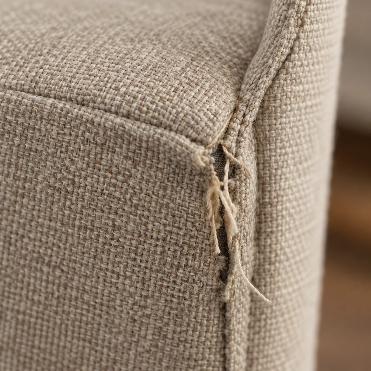 Split seam with loose threads on a taupe dining chair