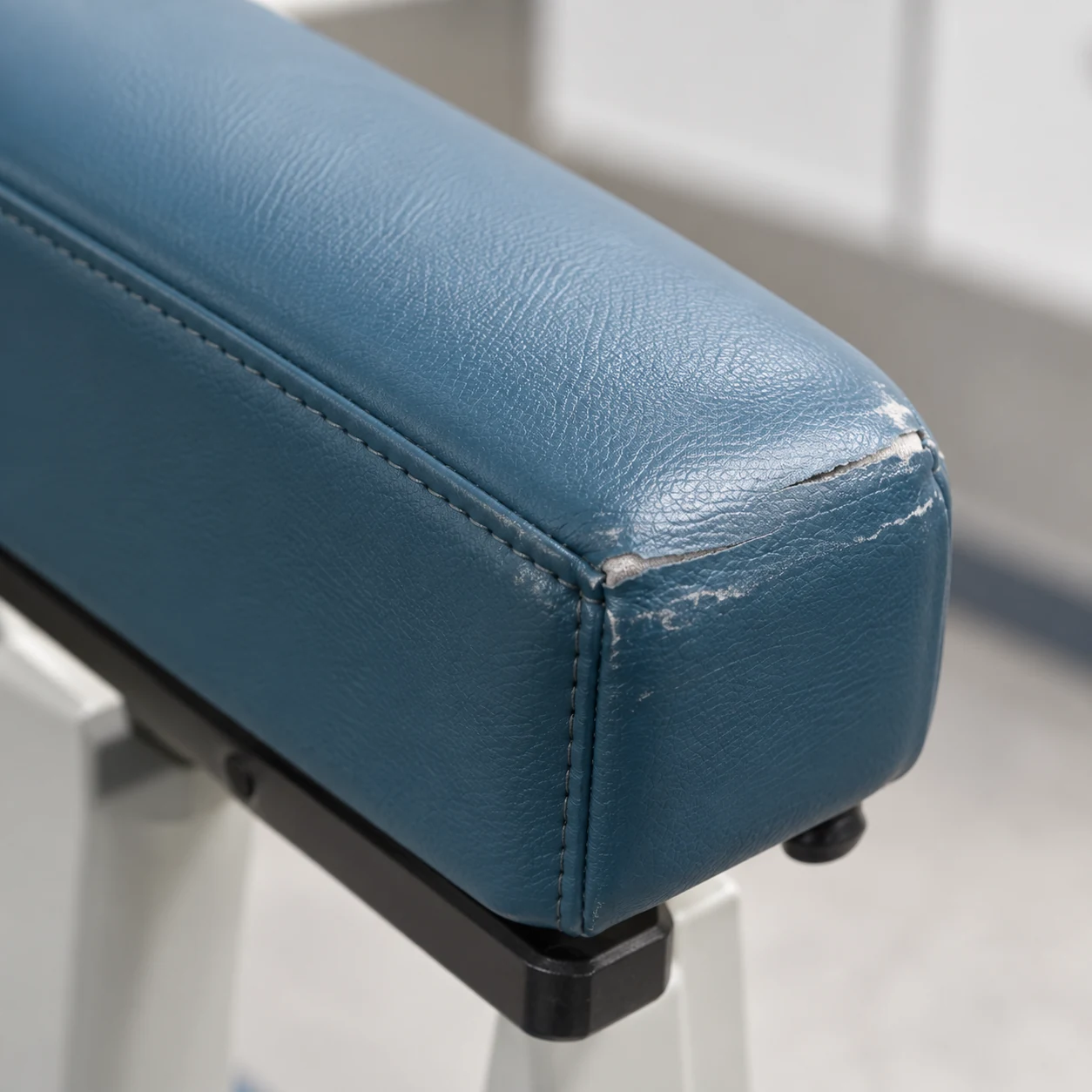 Worn treatment chair armrest pad split along its top corner