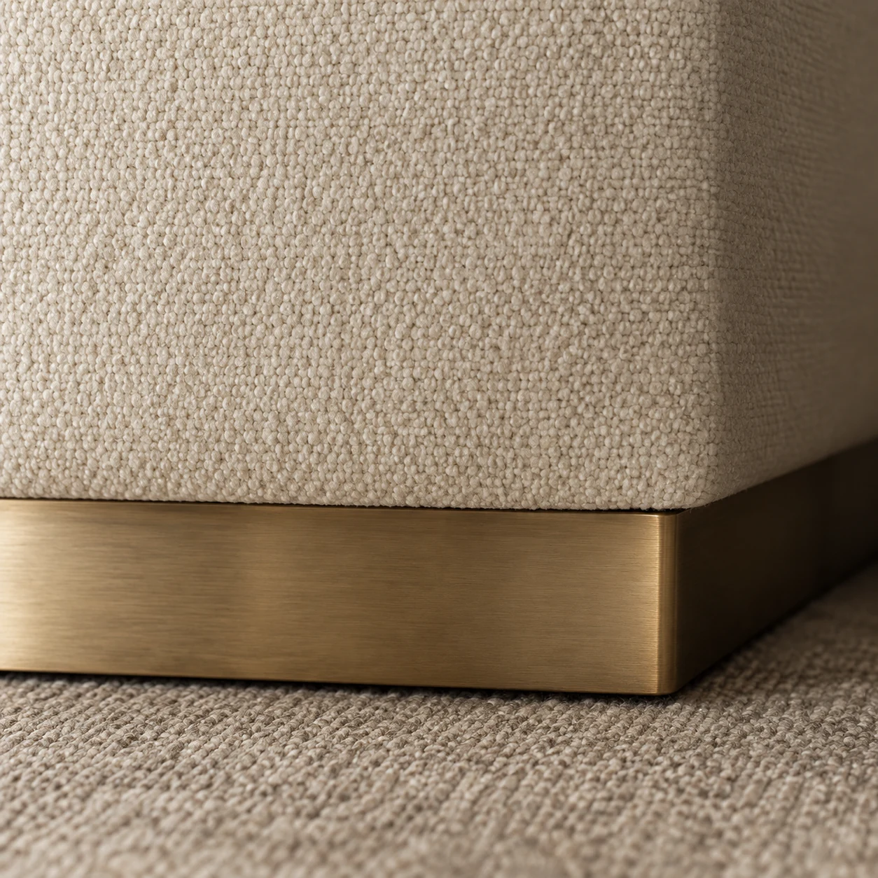 Brushed brass plinth base under a boucle upholstered corner