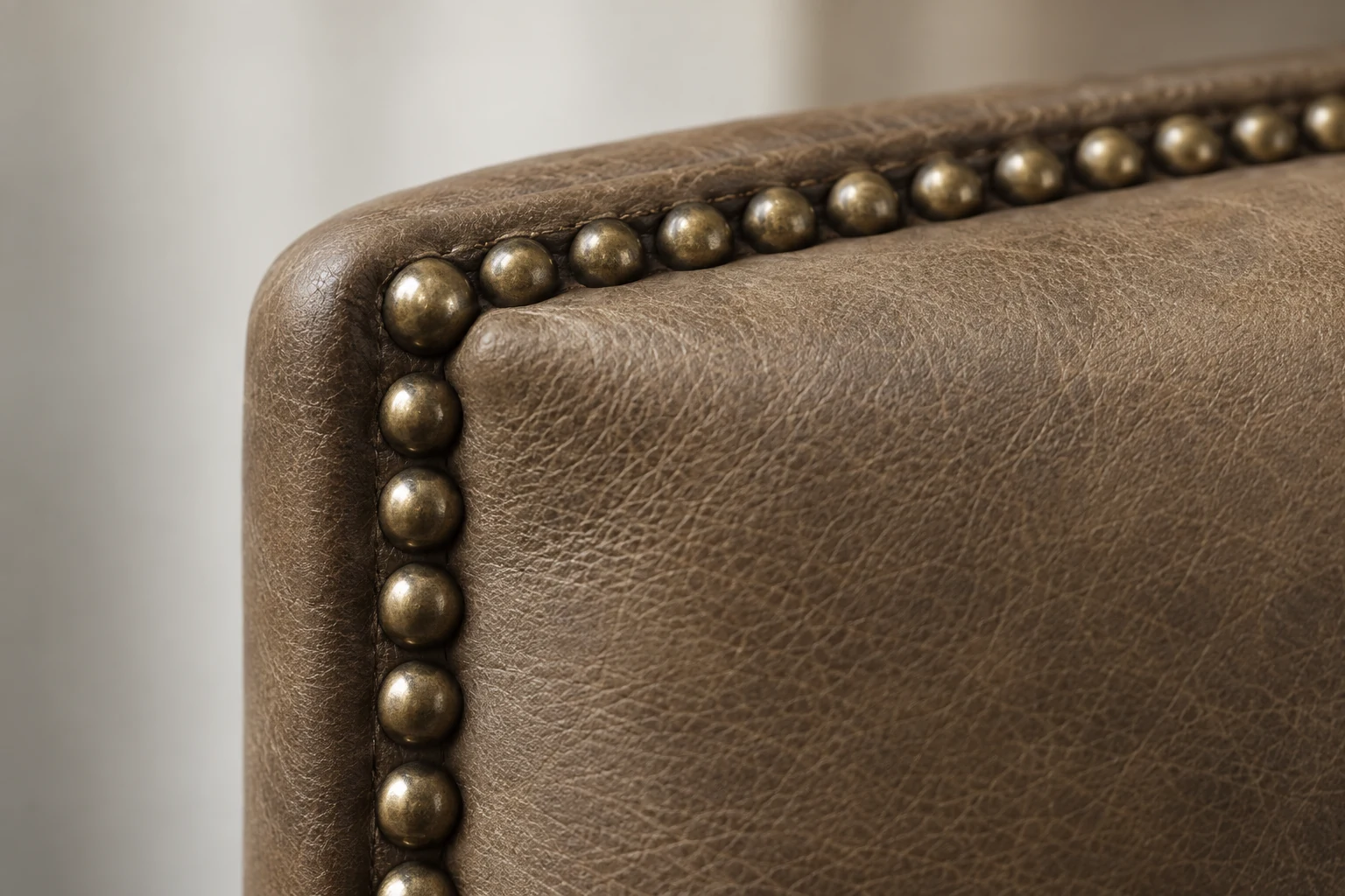 Antique brass nailhead trim along a leather chair back