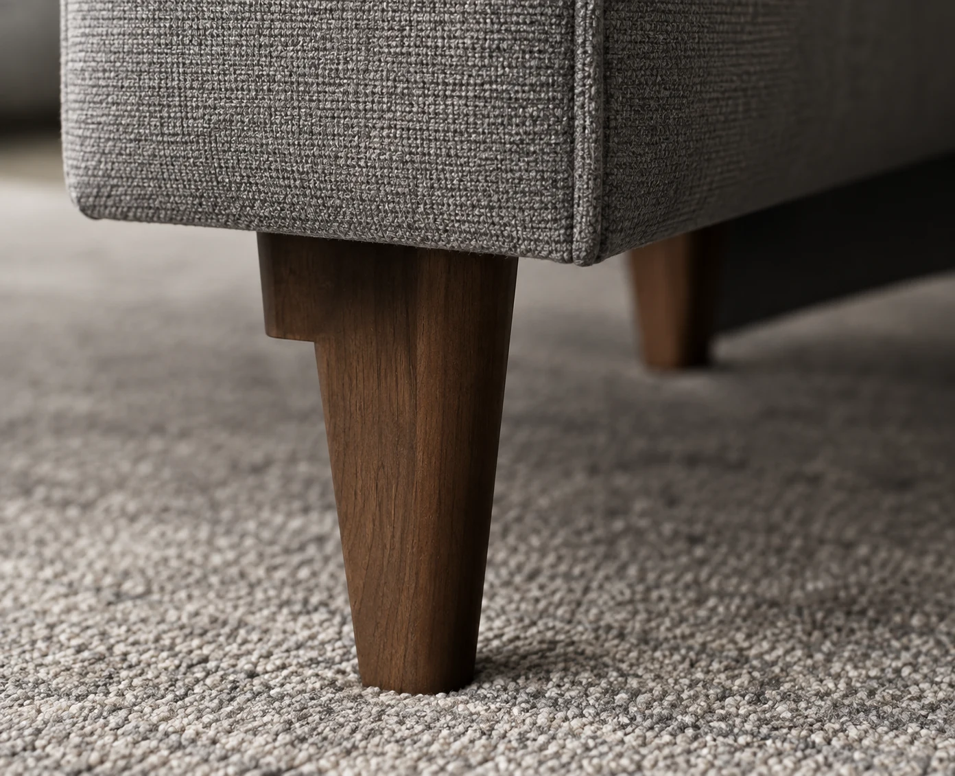 Tapered wood leg under an upholstered piece