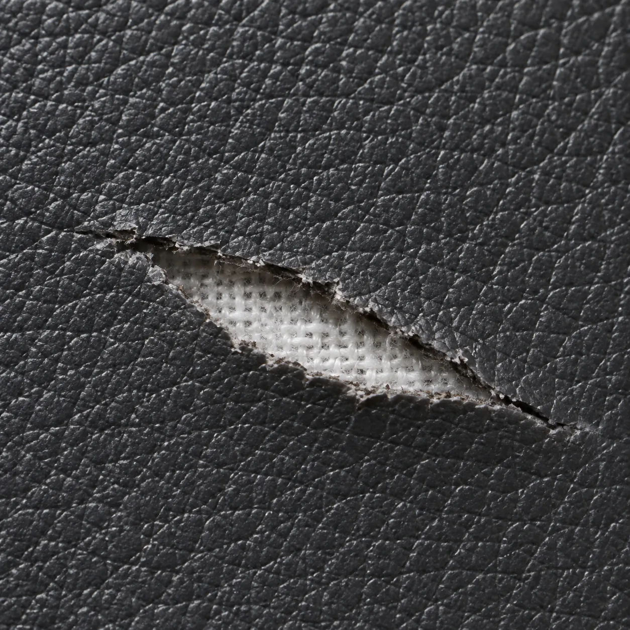 Close view of a split in vinyl exposing the woven knit backing