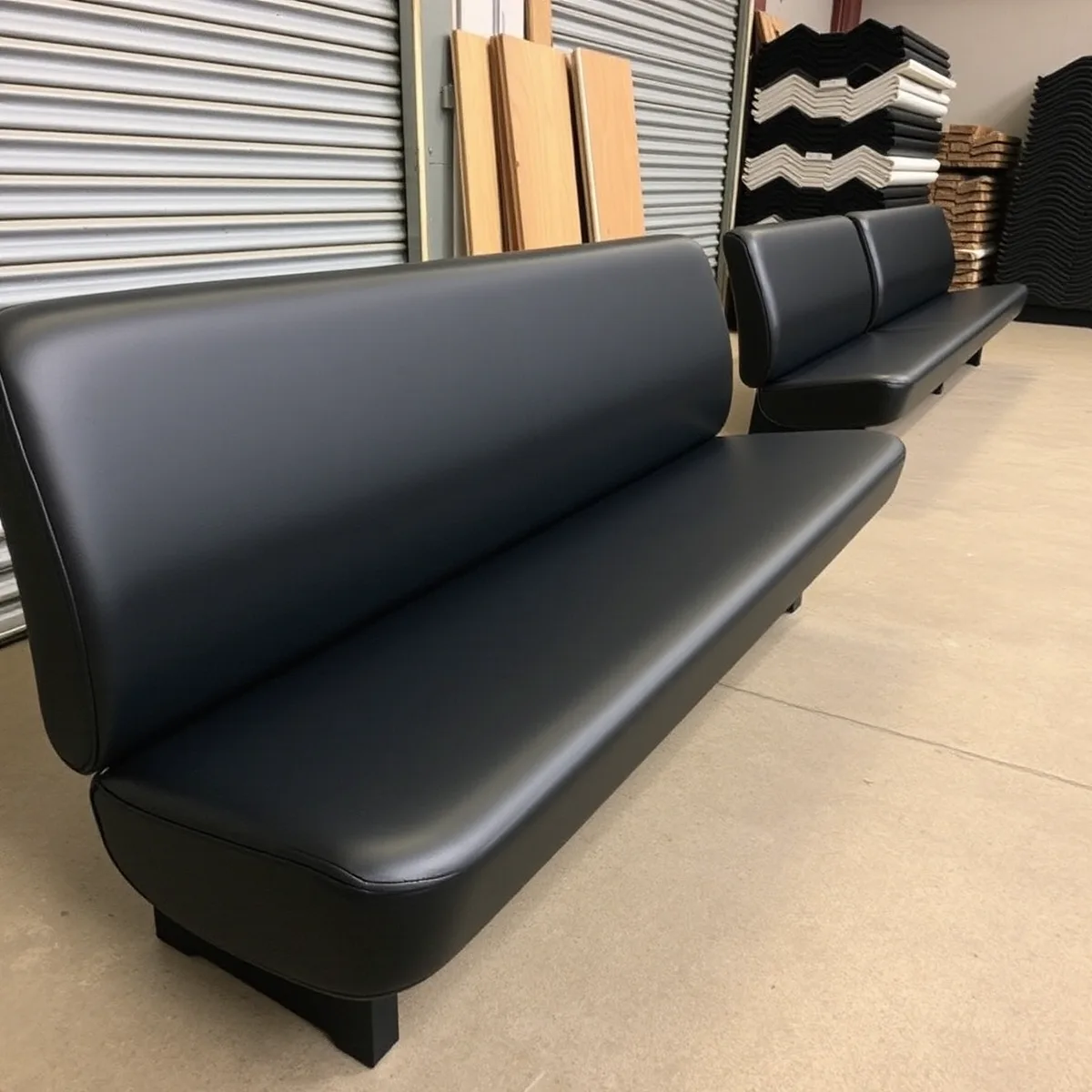 Refinished black vinyl bench seats lined up for return