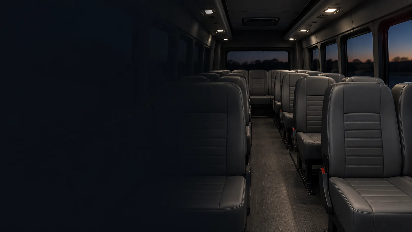 A vehicle interior in the evening with even, dark vinyl seats under the lights