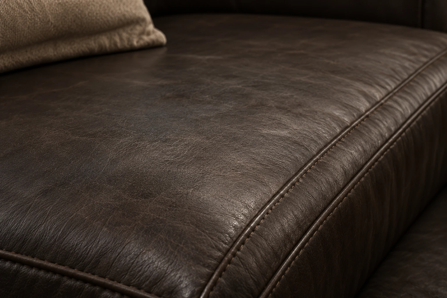 Macro view of a dark espresso leather seat panel with fine natural grain and a curved stitched edge