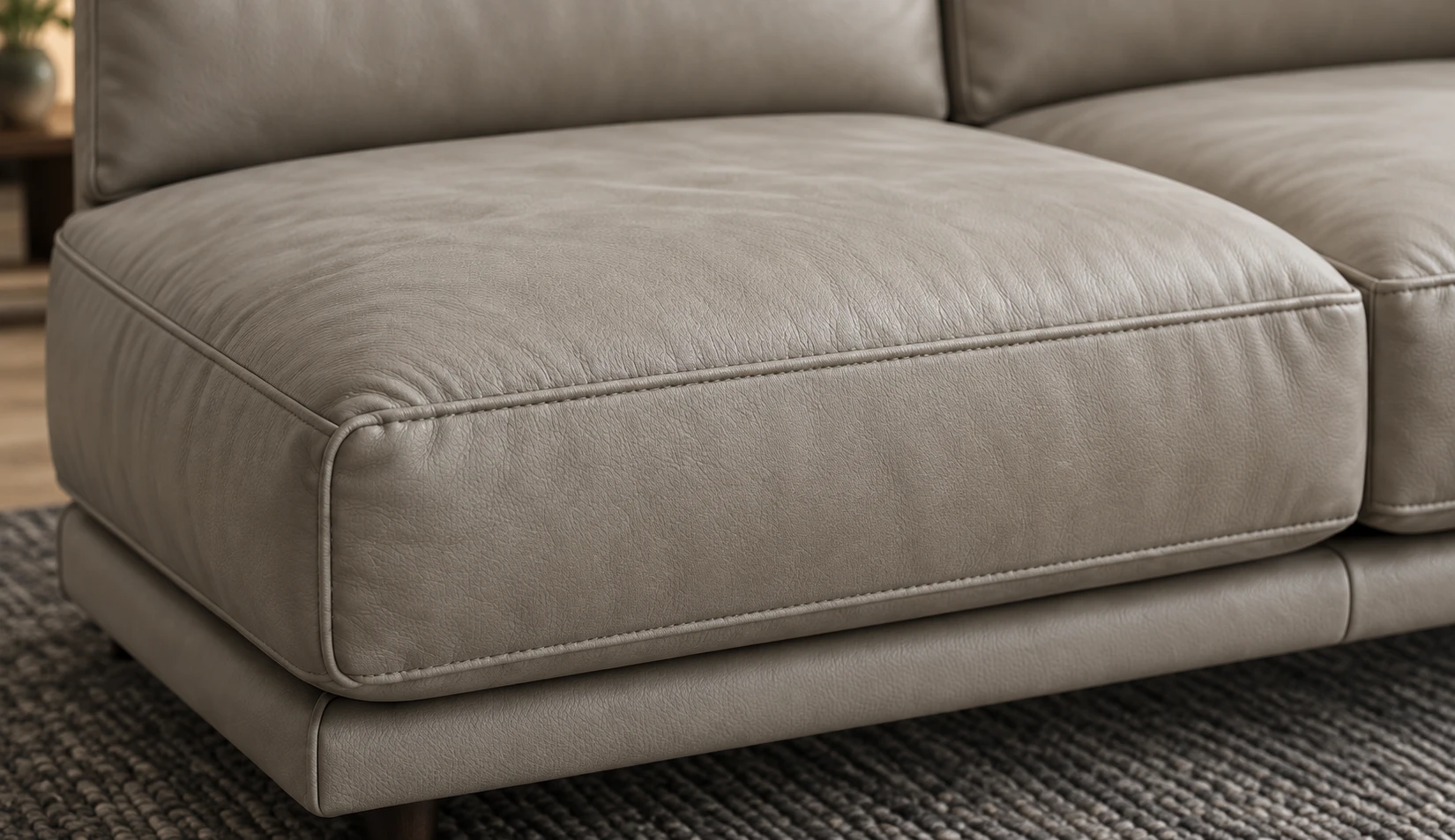 Close view of a pale greige leather seat cushion with soft creasing, on a dark textured rug