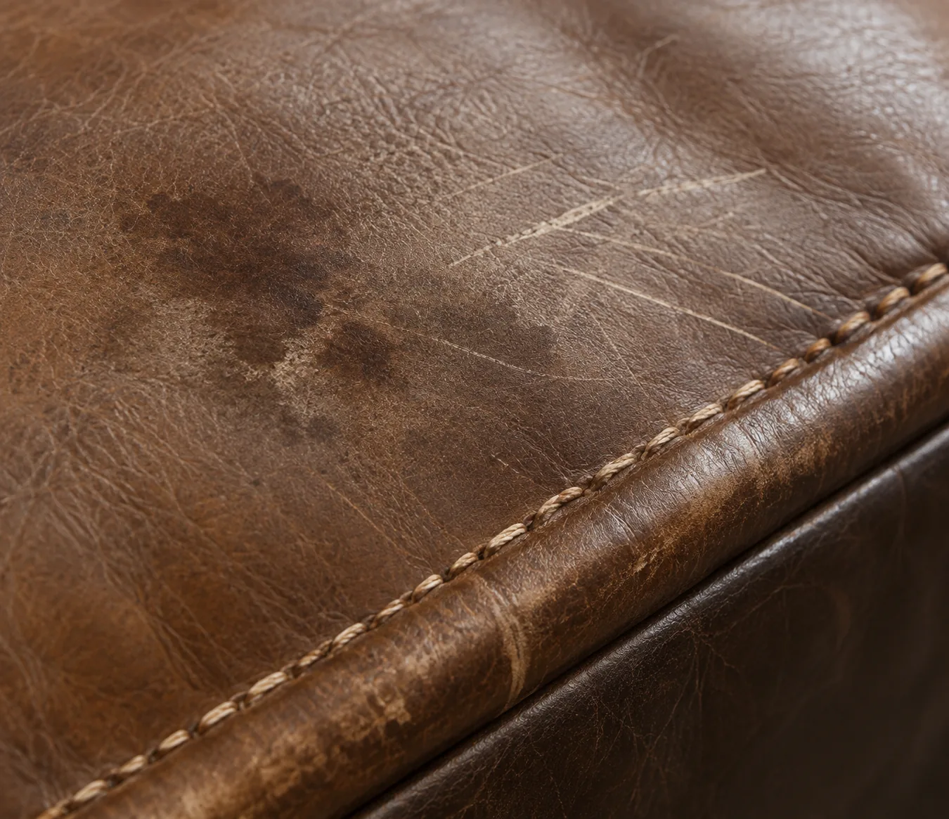 Brown bench leather rubbed thin either side of a long seam