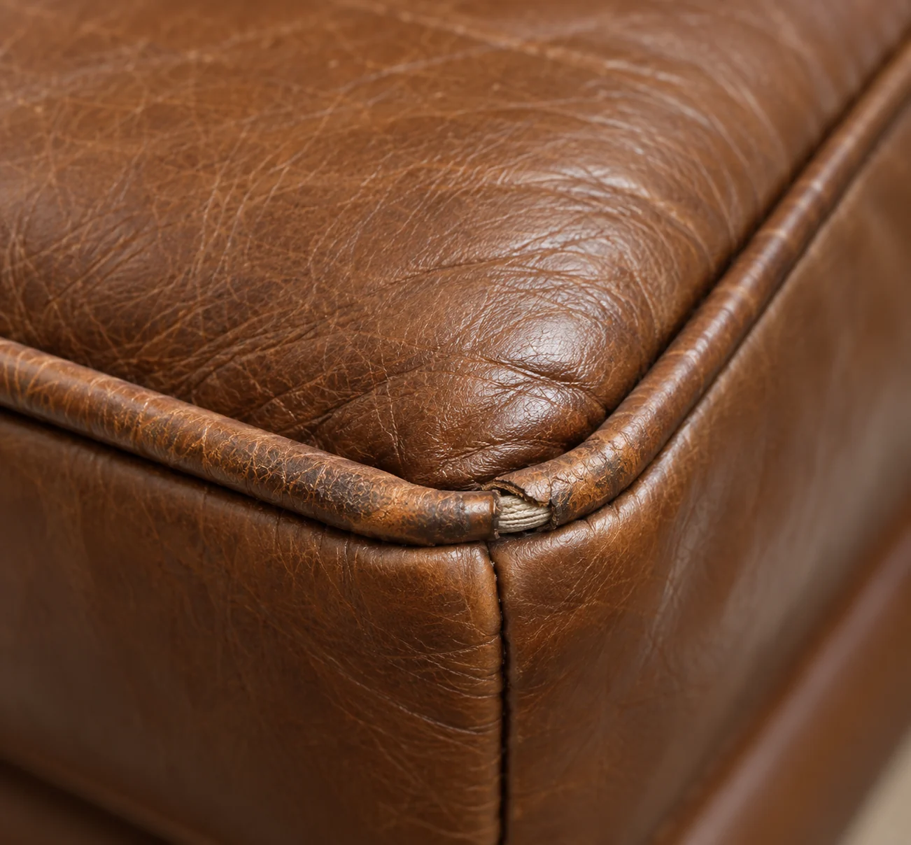 Worn piping on a leather ottoman corner